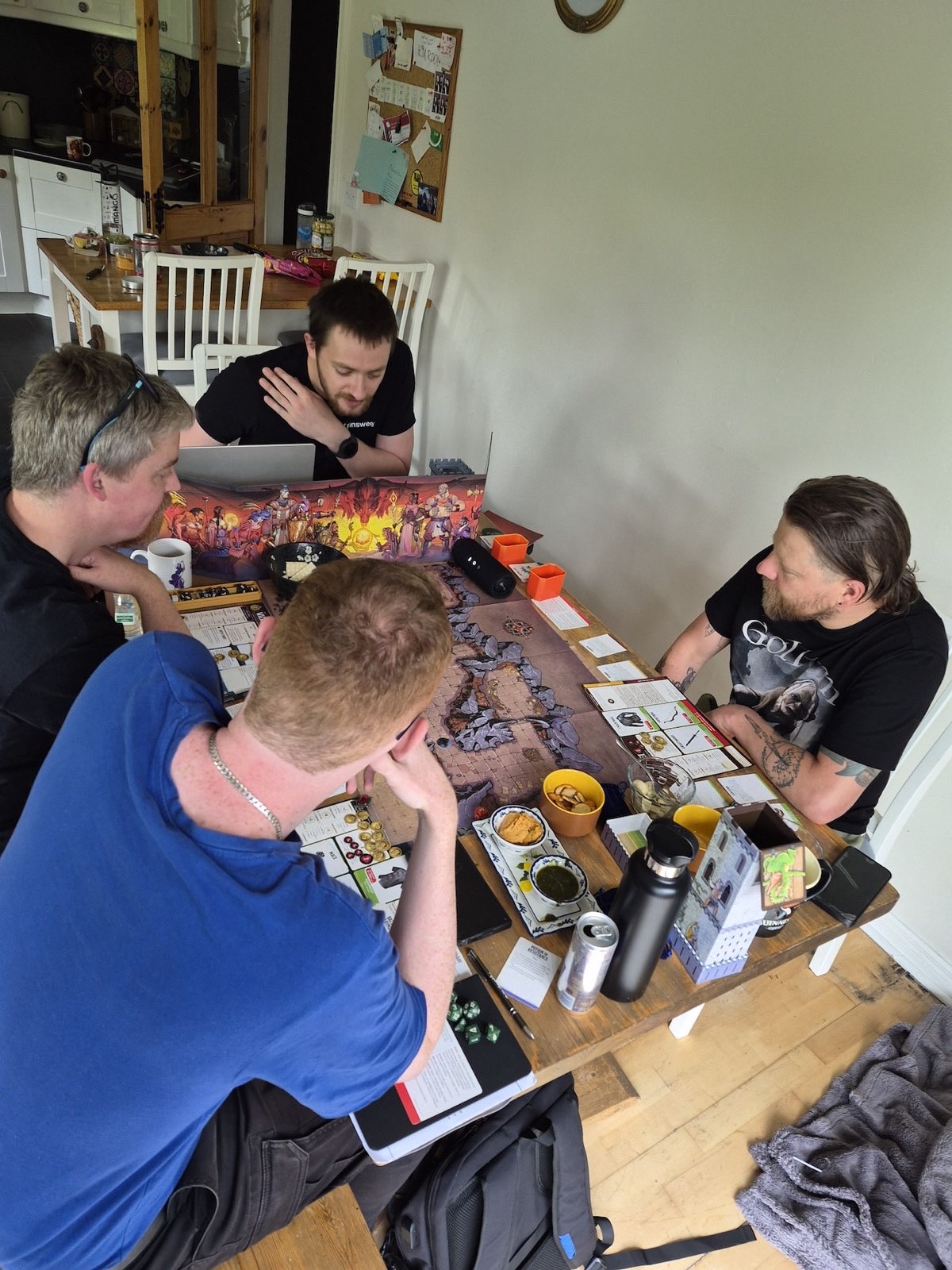 A group of adults gathered around a table playing a Dungeons & Dragons session, with dice, character sheets, and a dungeon map